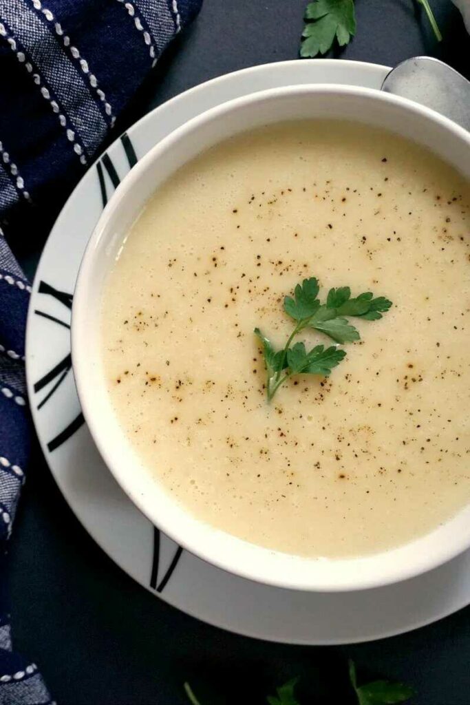Garlic soup thickened with bread served in a deep plate and garnished with fresh parsley.