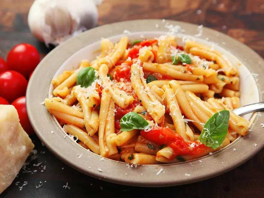 Pasta with tomatoes, basil and cheese served in a deep plate.
