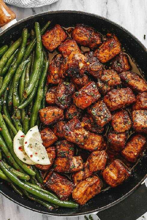 Pork in buttery garlic-lemon sauce with green beans served in a skillet.