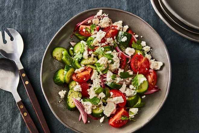Fresh vegetable and feta cheese salad served on a plate.