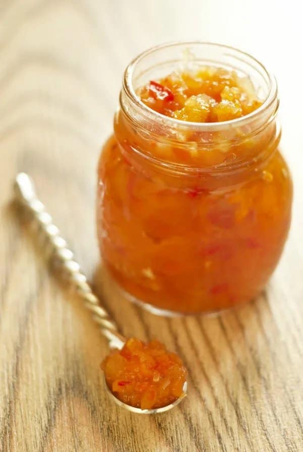 Apricot side sauce in a glass with a spoon next to it.