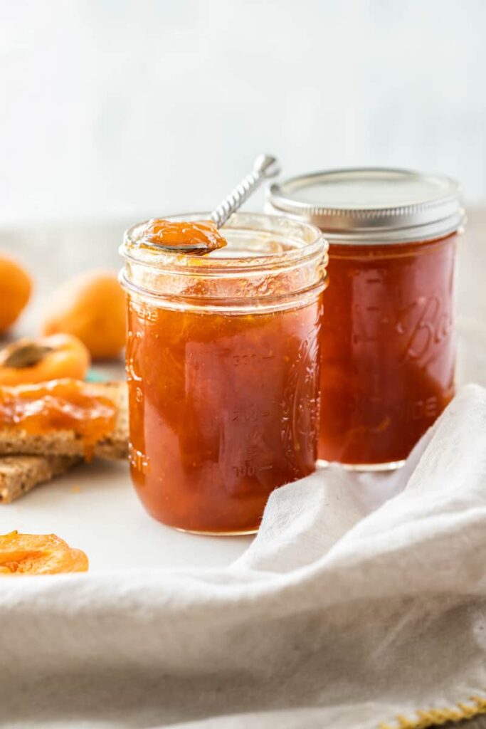 Two glasses of apricot jam placed side by side.
