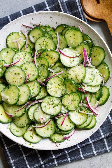 Cold and crunchy cucumbers and slices of red onion, topped with a luxurious herb dressing, all served on a plate.