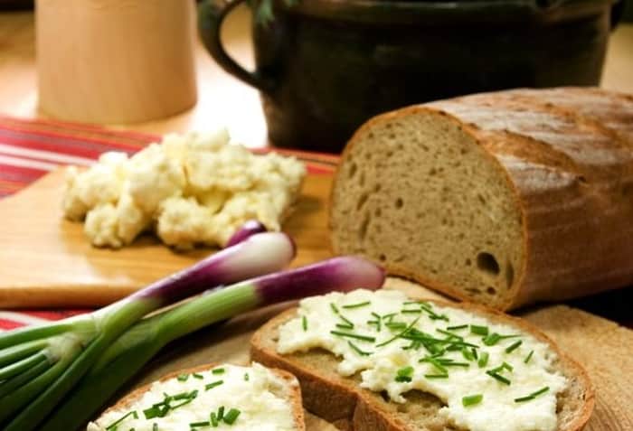 Pomazánka vytvořená ze sýru brynza a jarní cibulky namazaná na krajíci čerstvého chleba.