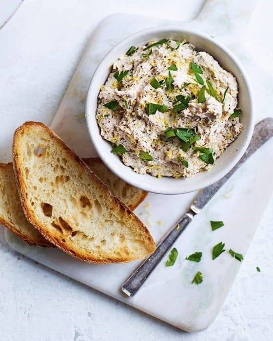 A bowl with a mixture of smoked mackerel, cream cheese and horseradish with slices of toasted bread.