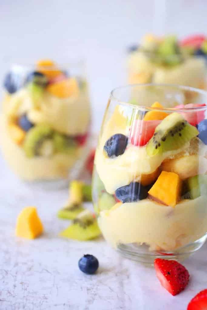 Dezert z vanilkového pudinku, čerstvého ovoce a cukrářských piškotů servírovaný ve sklenicích.