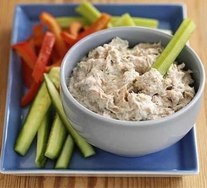 A dish with a spread made from cottage cheese, sour cream and smoked mackerel with pieces of vegetables.