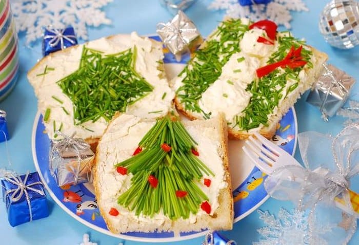 Slices of pastry decorated with brynza and chive spread with various winter motifs.