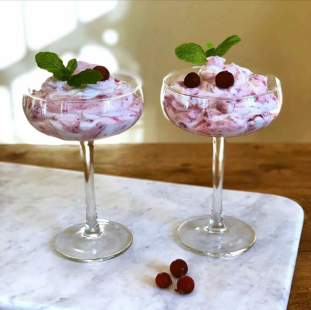 Dvě sklenice plněné krémem a ovocem, ozdobené čerstvou mátou.