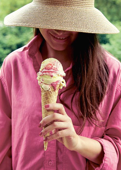 Žena s kloboukem, která drží v ruce vanilkovo-ovocnou zmrzlinu.