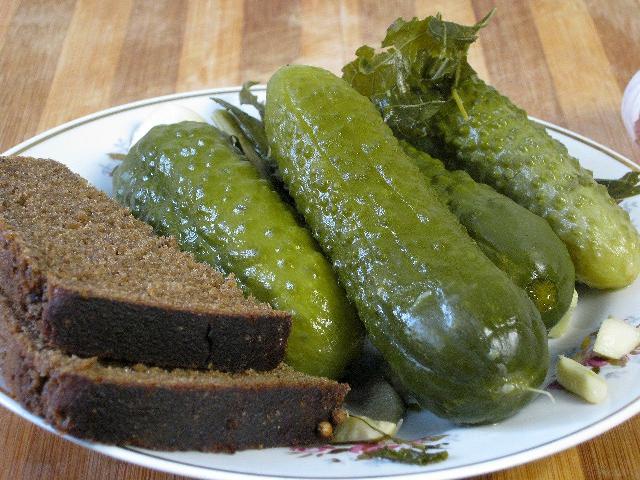 Pickled cucumbers on a plate with slices of dark bread.