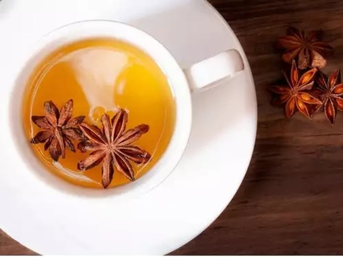A cup of star anise tea with pieces of spice.