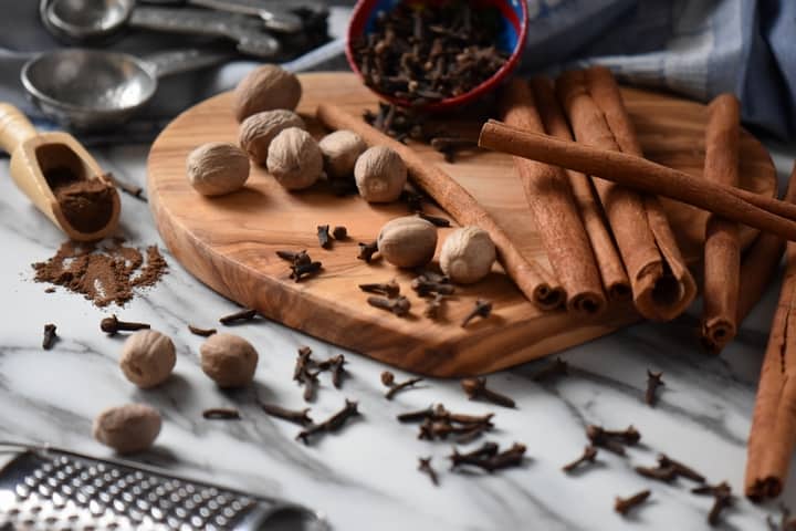 Cinnamon, nutmeg and cloves on a wooden board.