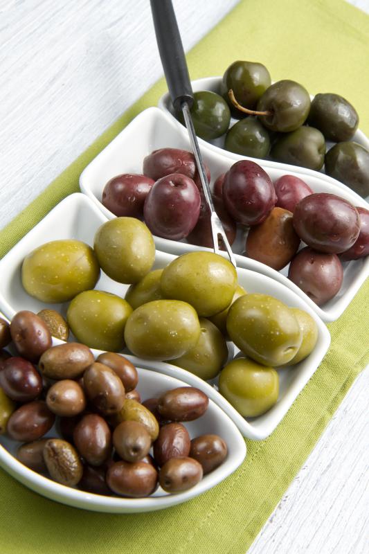 Different types of olives stacked in pots next to each other.