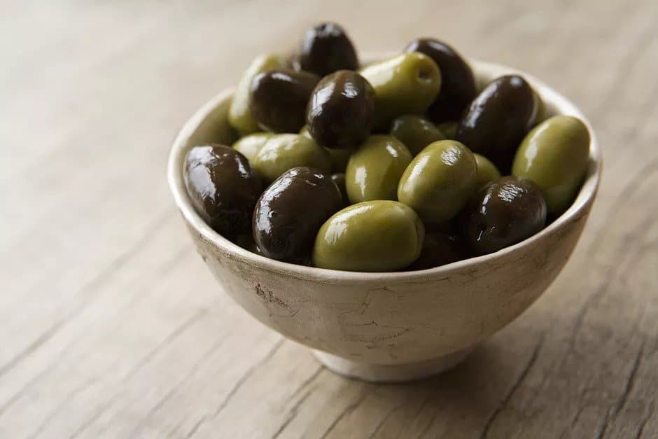 A bowl full of black and green olives.