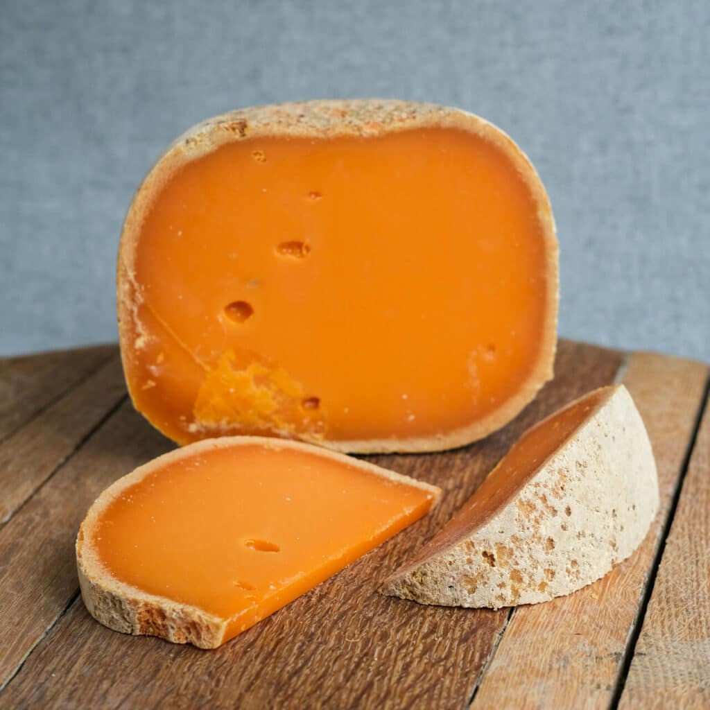 Sýr se svítivě oranžovou barvou a šedou kůrkou.