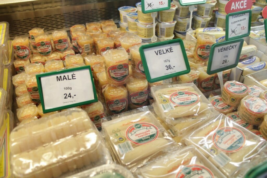 Regál plný různých typů tvarohového sýra v obalech.