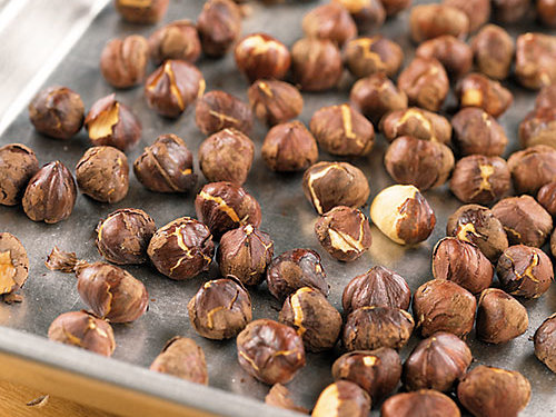 Shelled hazelnuts on a baking sheet.