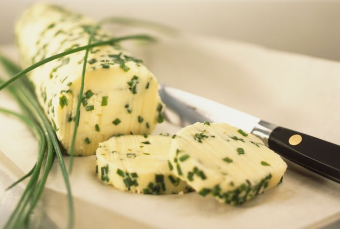 Chive butter on a cutting board with a knife.