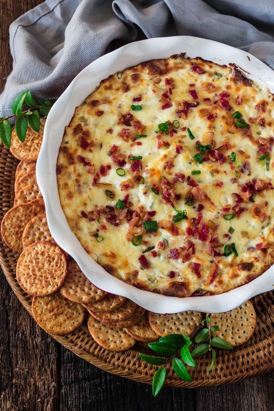 A bowl full of cheesy baked dip with crackers.