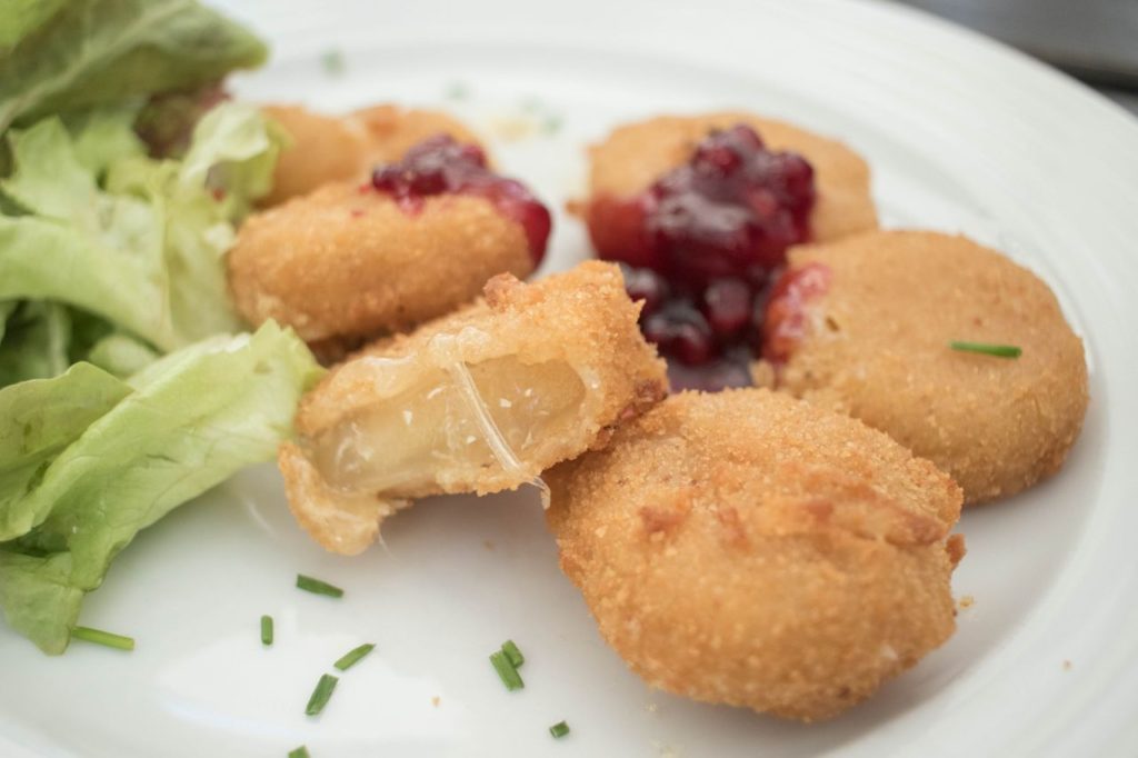 Cheesecakes wrapped in breadcrumbs fried in butter with vegetables.