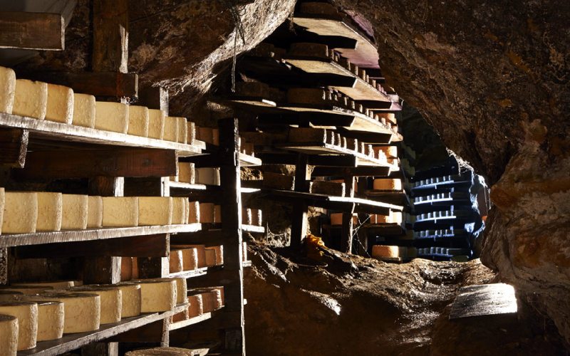 Přírodní vápencové jeskyně plné polic na kterých jsou umístěny sýry.