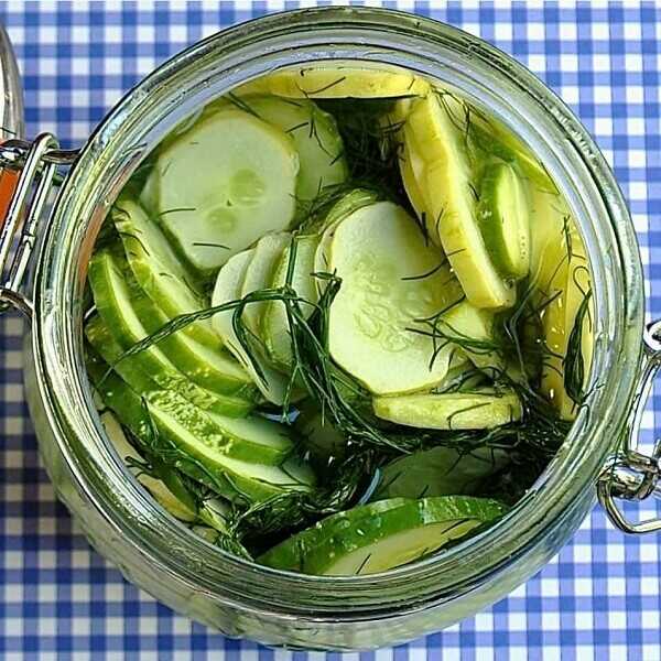 Pickled cucumber slices with dill in a glass.
