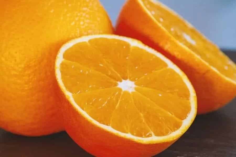 Eine frische ganze Orange und eine halbierte.