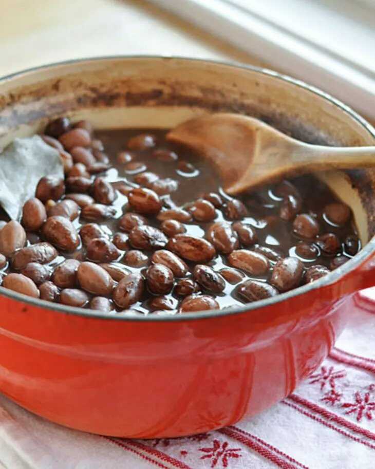 Vařené fazole v kastrolu s vařečkou.