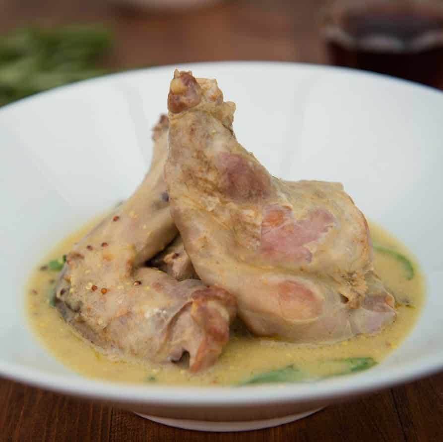 Rabbit legs in mustard sauce served on a plate.
