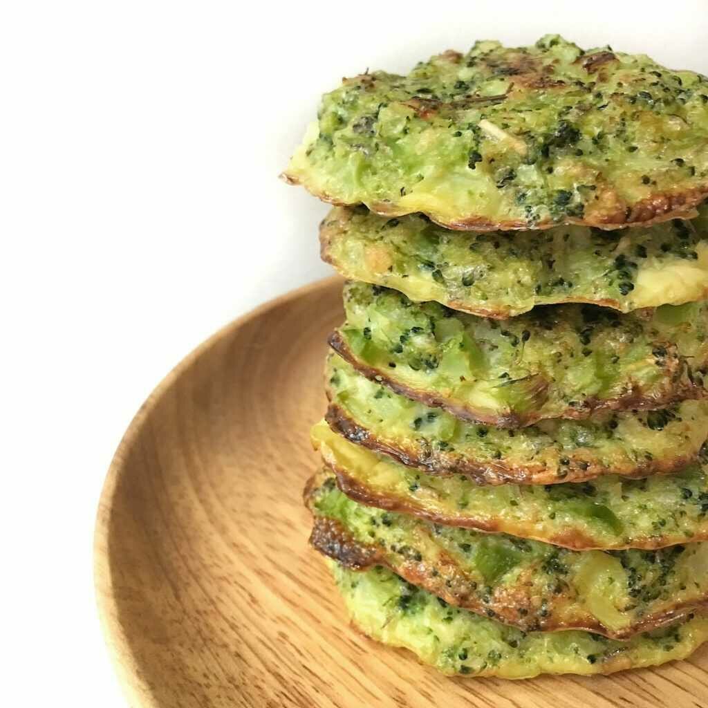 Broccoli meatballs with cheese stacked on top of each other and served on a plate.