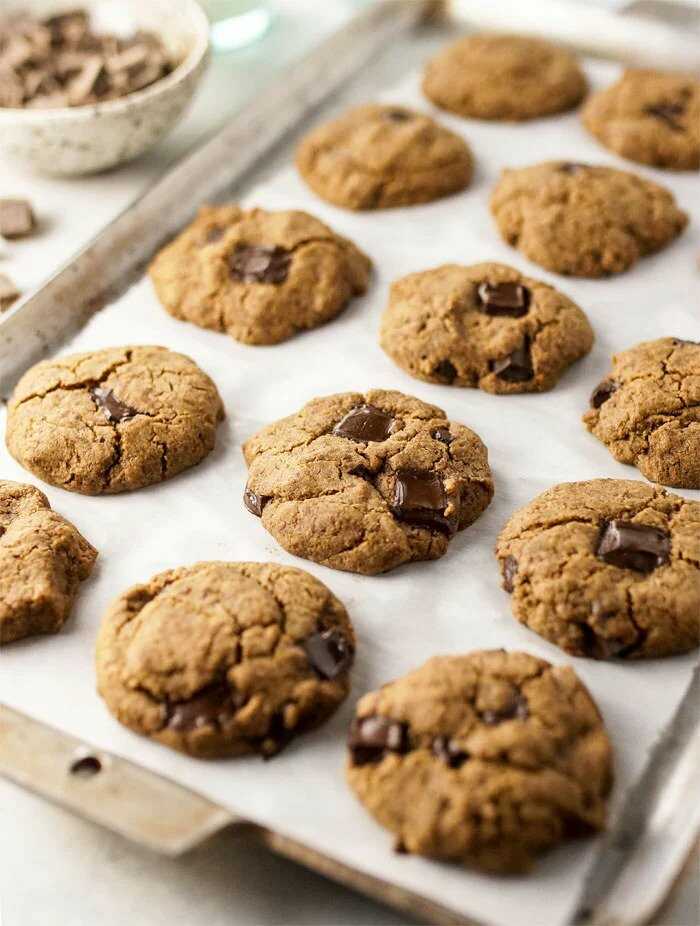 Buckwheat cookies with chocolate on a baking sheet lined with baking paper.
