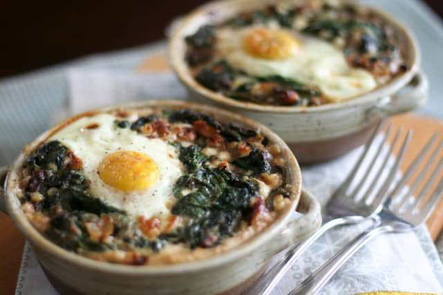 Two bowls with buckwheat, spinach and egg, next to which two forks are placed.