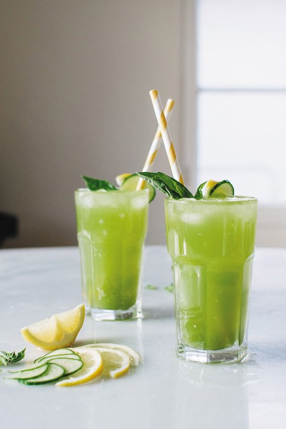 Sklenička plná zelené limonády ozdobená citronem a mátou.