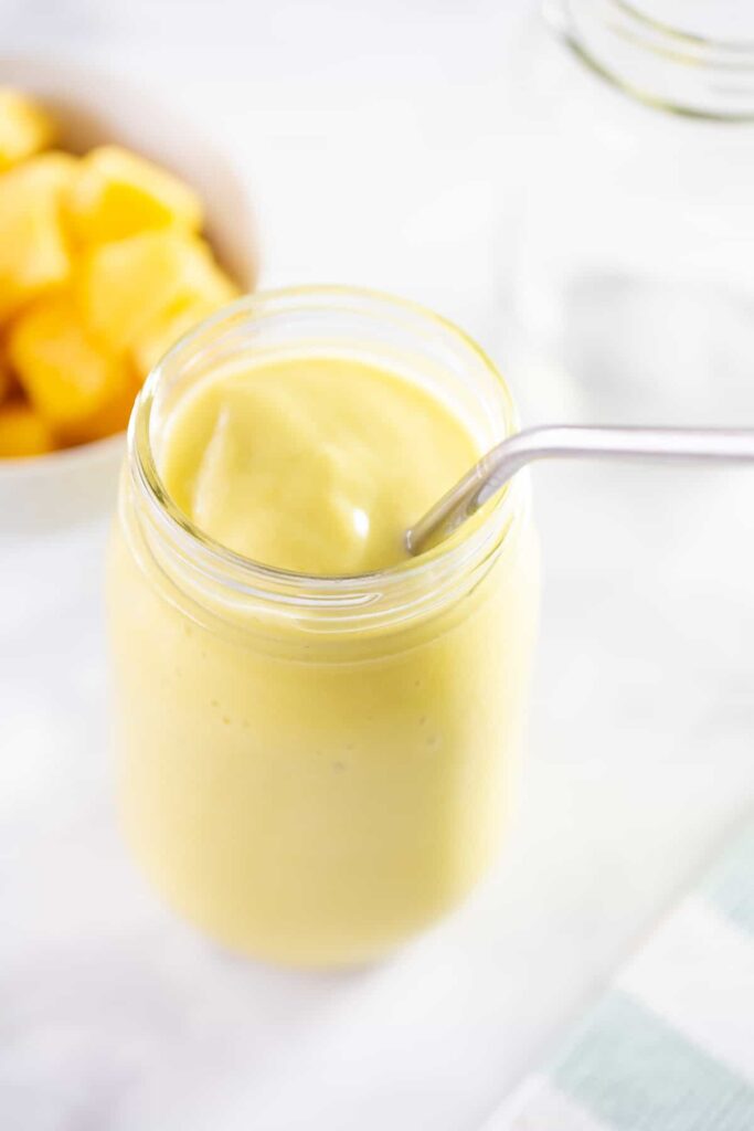Mangové smoothie s avokádem ve sklenici s brčkem.
