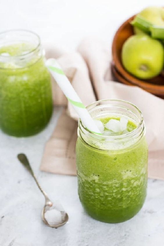 Apple smoothie with celery in a glass with a straw.