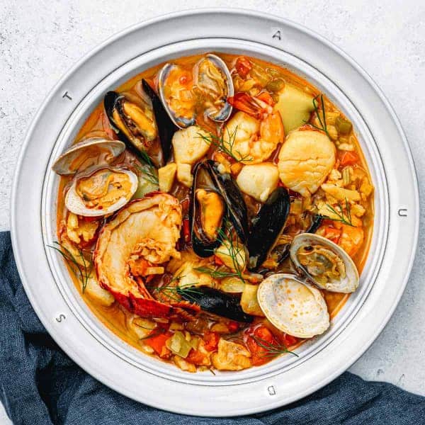 Polévka z ryby a mořských plodů servírovaná v hlubokém talíři.