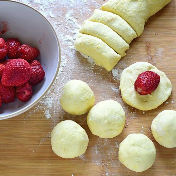 Fluffy yeast dough with fresh strawberries for wrapping.