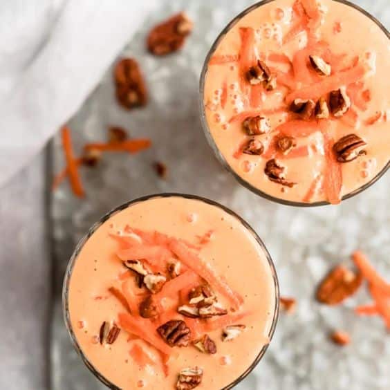 Smoothie made of fresh ingredients decorated with nuts and carrots.