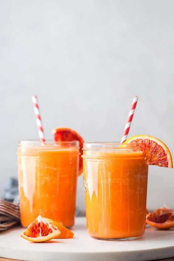 Ein köstliches gesundes Getränk aus Äpfeln und Karotten, garniert mit einer Orange.