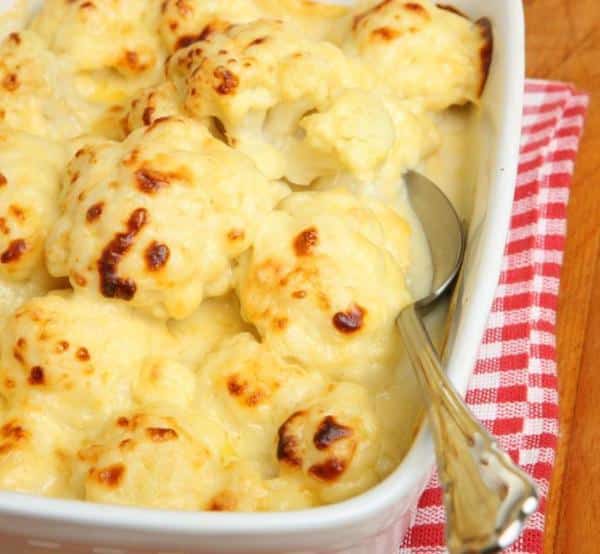 Cauliflower gratin in a baking dish with a spoon.
