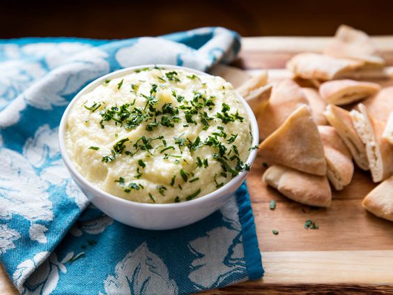 A bowl full of creamy spread with pita.