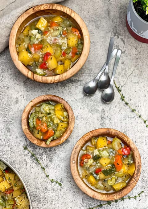 Dušená kedlubna s řapíkatým celerem, paprikou, mrkví a cuketou servírovaná na talířích s vedle položenými lžičkami.