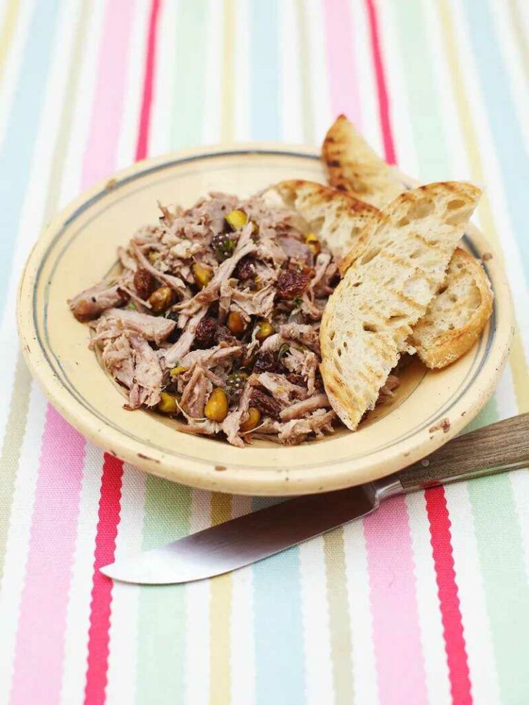 Shredded duck meat on a plate with toasted bread. A knife is placed next to it.