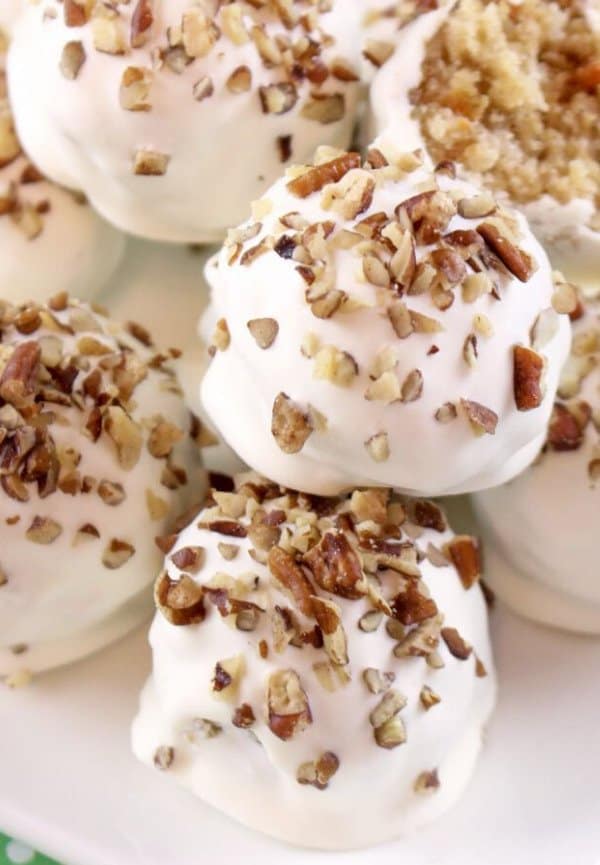Carrot truffles covered in white chocolate and decorated with chopped nuts.