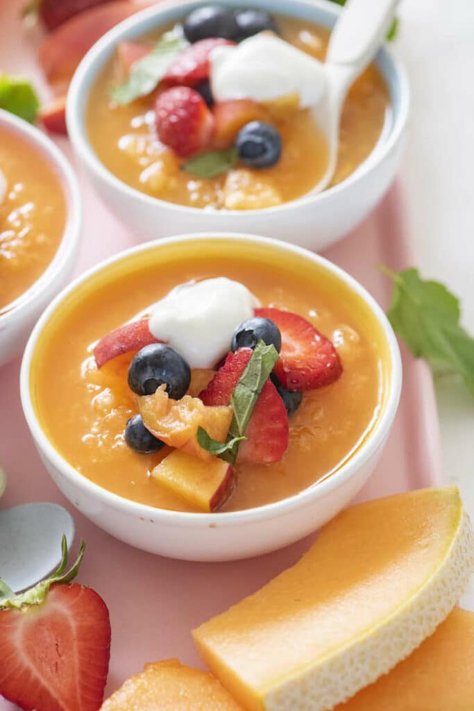Melounová polévka v mističkách, ozdobená čerstvým ovocem a jogurtem.