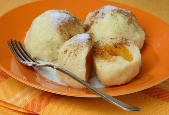 Apricot dumplings served on a plate with a fork, sprinkled with sugar.