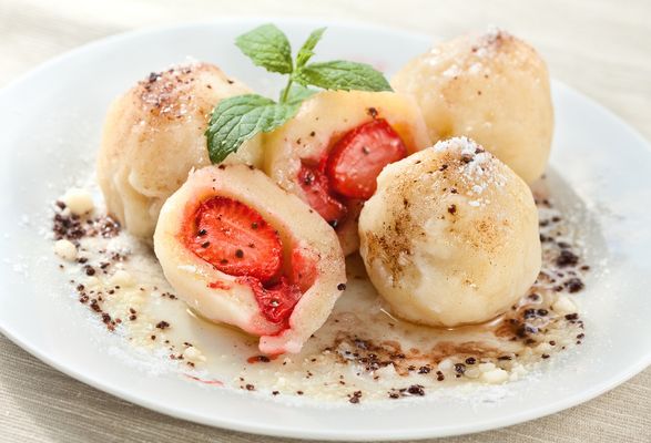 Cottage cheese dumplings with strawberries served on a plate.
