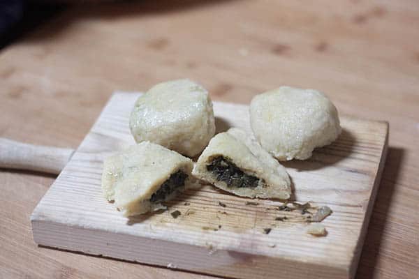 Dumplings filled with spinach on a wooden board.