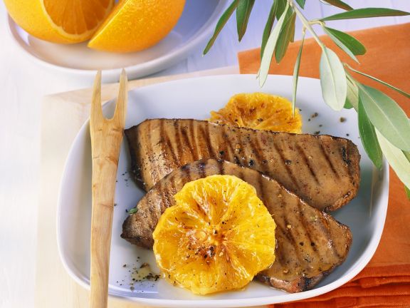 Grilled liver served on a plate with oranges.